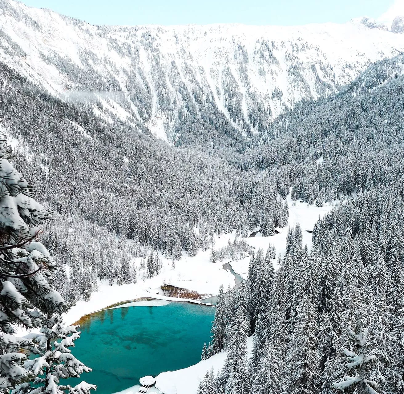 A lake in the middle of a snowy Alpine valley