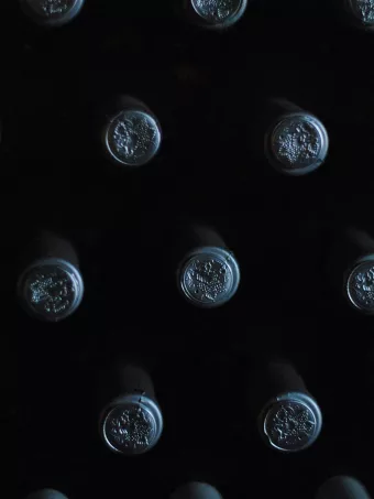 Vue rapprochée d'un présentoir à bouteilles, montrant les bouchons en relief alignés dans un éclairage tamisé.